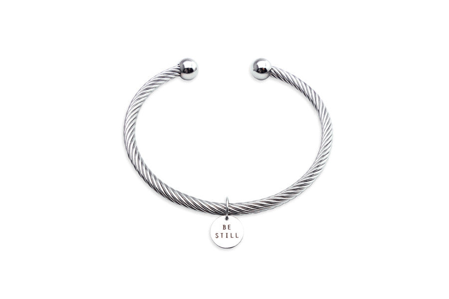 Be Still engraved on round pendant on rope bracelet